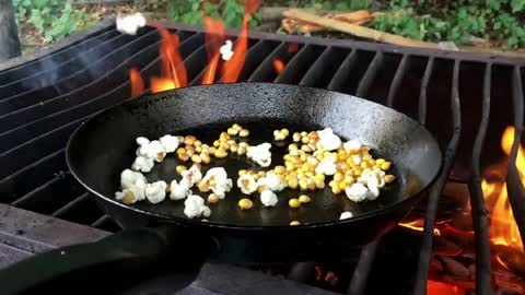 Popcorn popping in slow motion outside on a grill