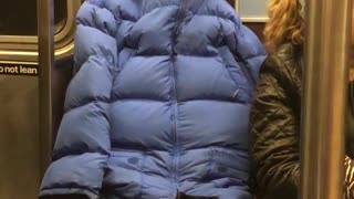 Person subway blue puffy jacket tied holes covered