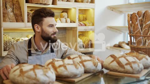 The Male Vendor In The Bakery Shop Bringing Just Baked Bread To The Counter