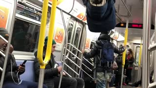 Little boy climbs ceiling handrails and hangs upside down in subway train