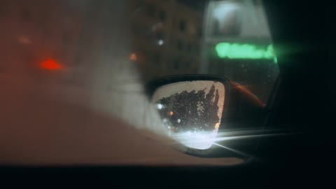 View of City Traffic at Night through Car's Side View Mirror