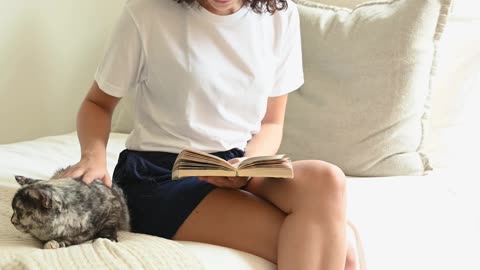 Woman Sitting on the bed Petting a cat while reading a book Funny Videos