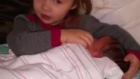 Big sister singing " Baby Mine" to newborn baby brother