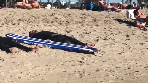 Three guys in wetsuits lay out on the beach