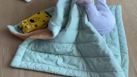 Baby playing alone on the duvet.