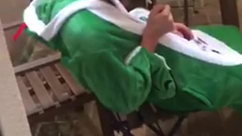 Guy wearing green onesie smoking cigarette