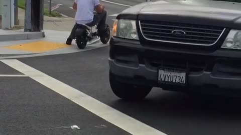 Man in white riding kid motorcycle on street