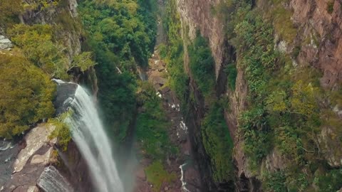 A waterfalls from high atop a mountain to a river