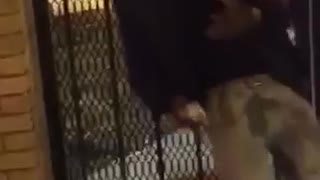 Drunk black guy tries to stand up and walk but falls back to fence