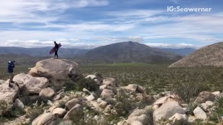 Guy takes picture with surfboard in the middle of the desert