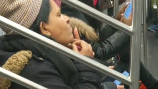 Woman pulling chin hair subway wearing beanie