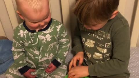 Big brother reads to little brother in his crib