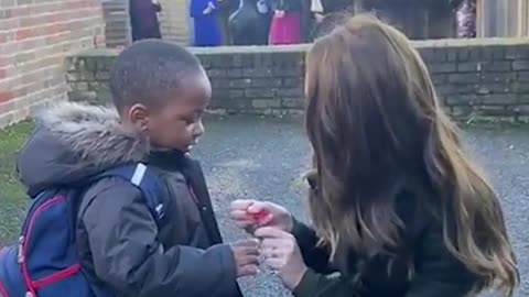 Sweet moment Kate hands her poppy to a 3year-old boy