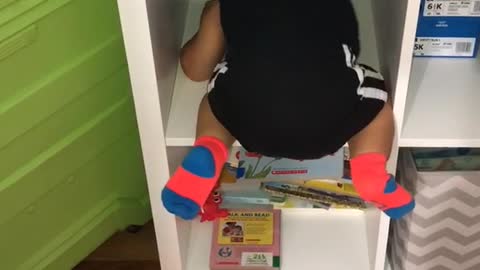 Baby climbing into cubby shelf