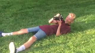 Red shirt guy lies on back to get photo girl near covered wagon