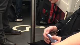 Woman rests her bare feet on her backpack on subway train