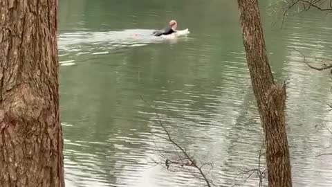 Surfer paddles surfboard in a river