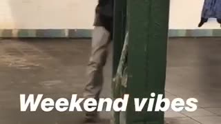 Guy dances with a metal beam inside subway station