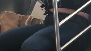 Blonde woman puts hair extension on in subway