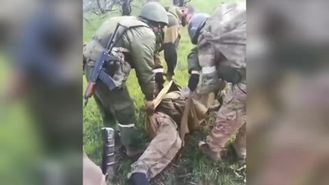 Russian soldiers carry a wounded Ukrainian serviceman