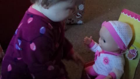 Playful baby has precious reaction to new doll