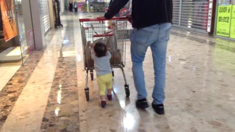 Toddler adorably helps daddy push cart