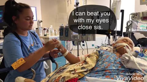 Intubated pediatric patient plays thumb war with sister.