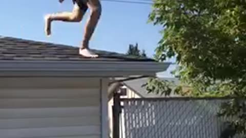 Man in striped shorts jumps from roof to white pool floatie