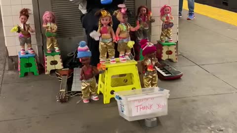 Man plays old mcdonald on blue melodica with dozens of dancing puppet dolls around him