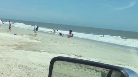 Couple eating in car watch two people attempt to use raft in ocean