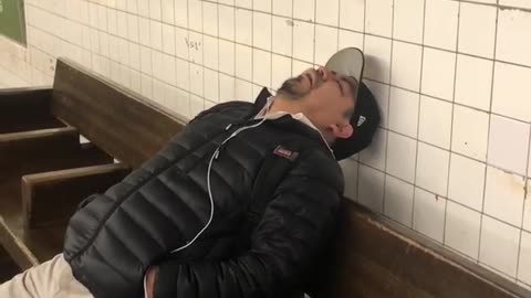 Man falls asleep on subway station bench and snores loudly