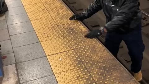 Man hops down to subway train tracks and picks up dropped item, climbs back up