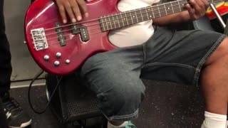 Man hanging from subway plays red guitar