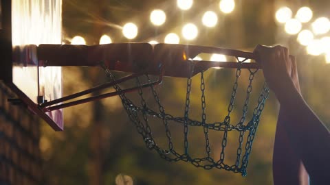 Man dunking the ball in a basketball hoop at night