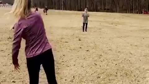 Girl purple jacket tosses football to friend green jacket falls