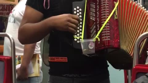 Man plays red accordion with dog sitting on top