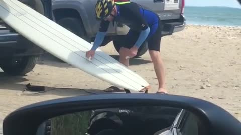 Guy cleans white surf board on car