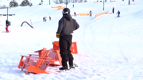 Guy tries to grind over orange chairs, crashes into and knocks down chairs