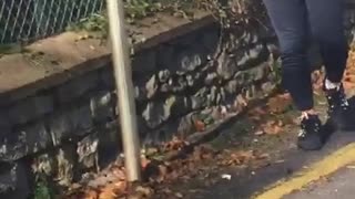 A guy in black jumpsuit jumps fence falls