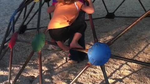 Little girl yellow climbing jungle gym dome falls forward and into wood chips
