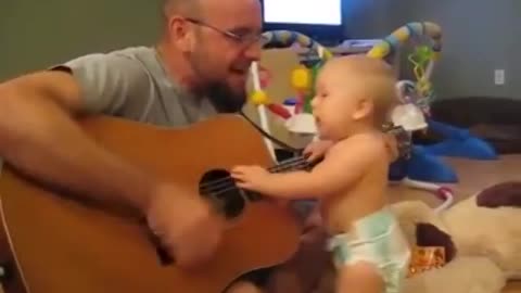 a beautiful baby dances and sings to the sound of the guitar