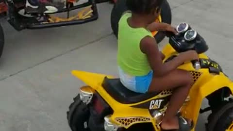 A Toddler learns to drive four Wheeler with his dad