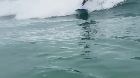 Guy in blue wet suite surfing high fives guy filming