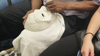 Man on subway train carving a white mask