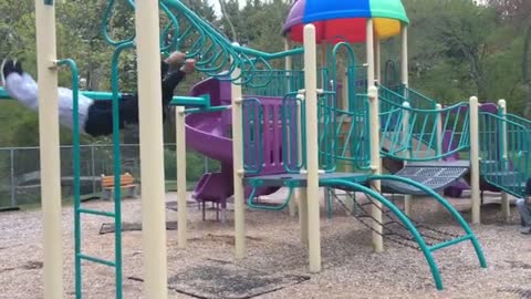 Guy tries to do a reverse backflip on monkey bars at a park.