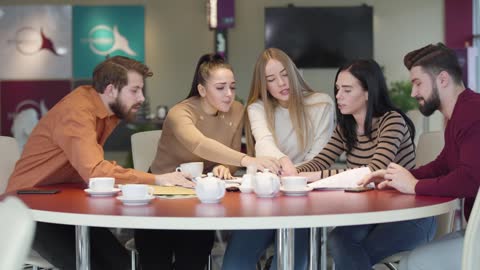 Students in a cafeteria discussing an assignment