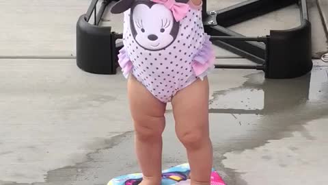 Small girl pink bathing suit stands on boogie board