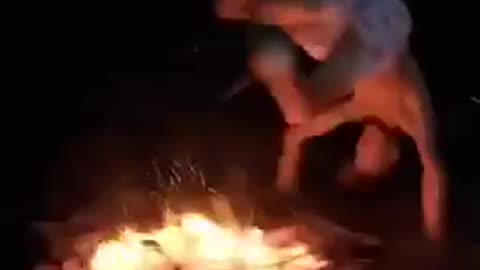 Shirtless men jumping over bonfire