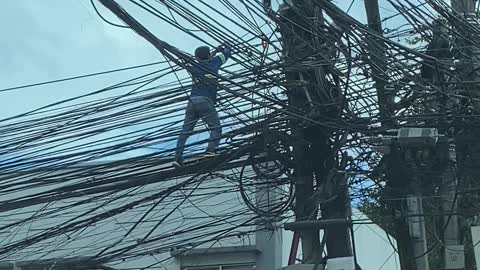 Worker Climbs Along Electric Wires