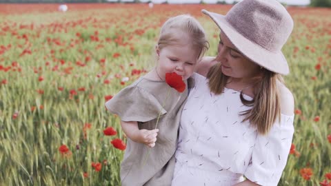 Woman Carrying Her Child While Standing on Red Poppy Flower Field